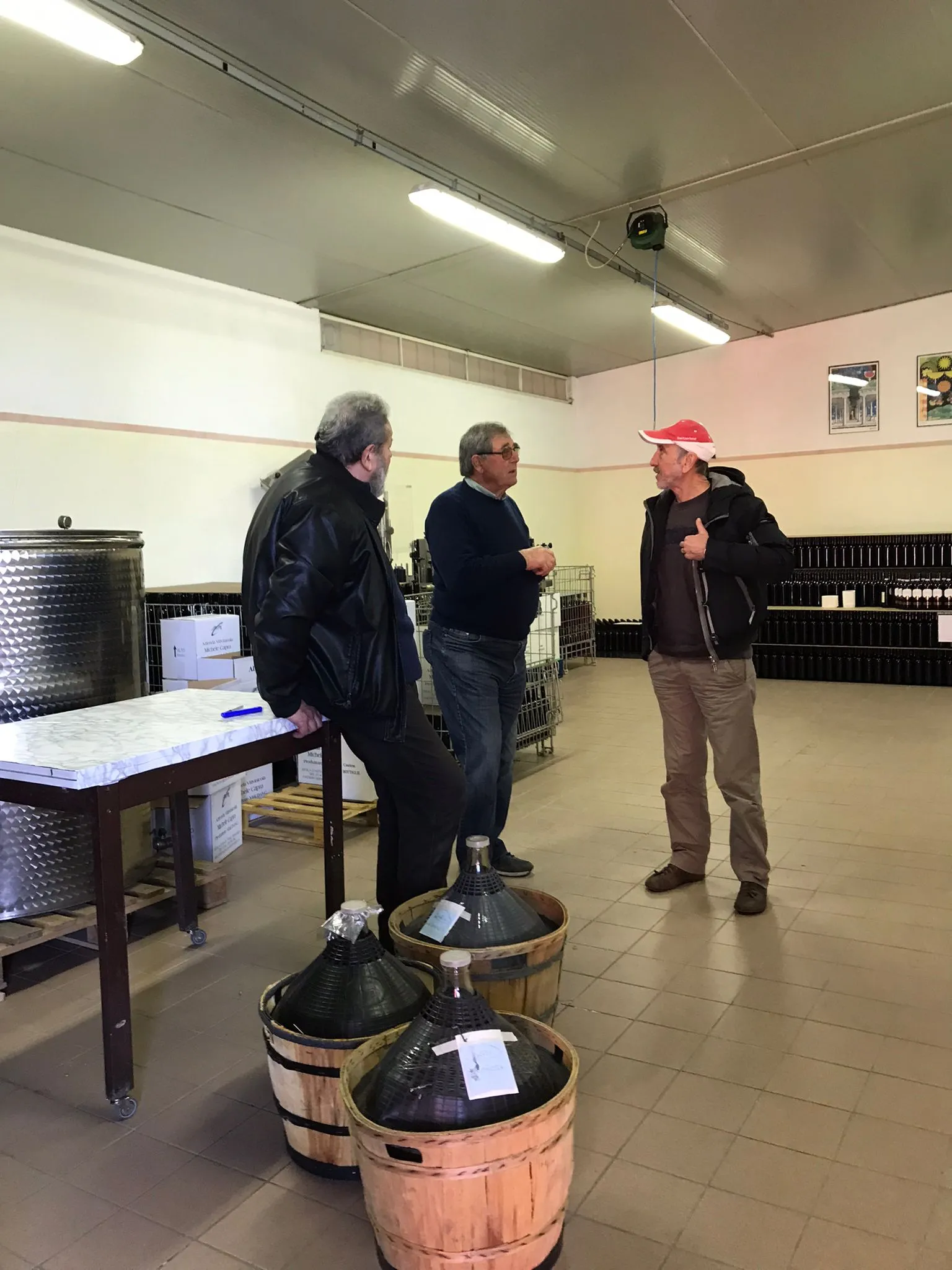 Luigino prende gli ordini per riempire damigiane, con clienti in cantina, nella azienda vitivinicola Michele Capra