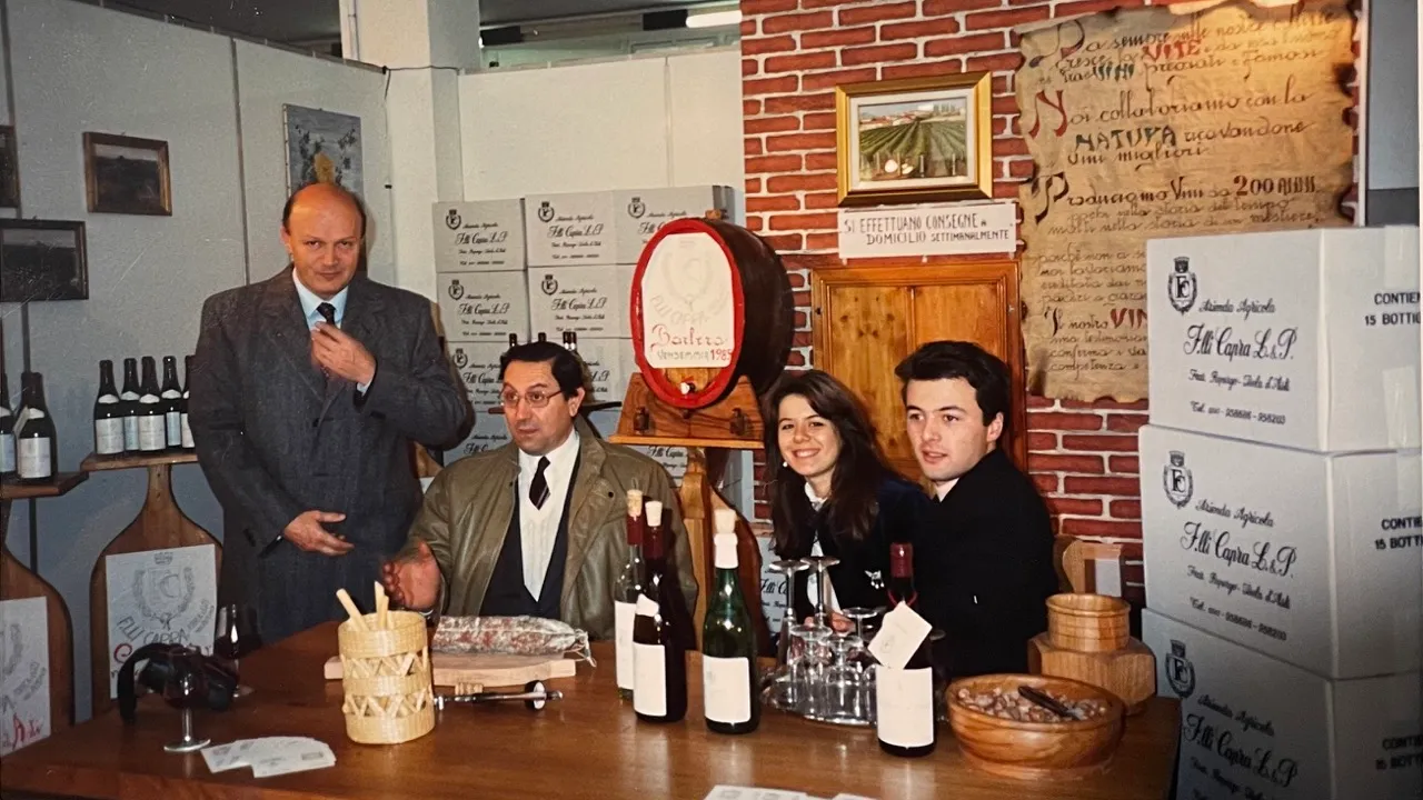 Padiglione dell'azienda vitivinicola Michele Capra, con scatole di vino, bottiglie, cibo, la pergamena che teniamo in cantina, Michele, sua moglie e i clienti