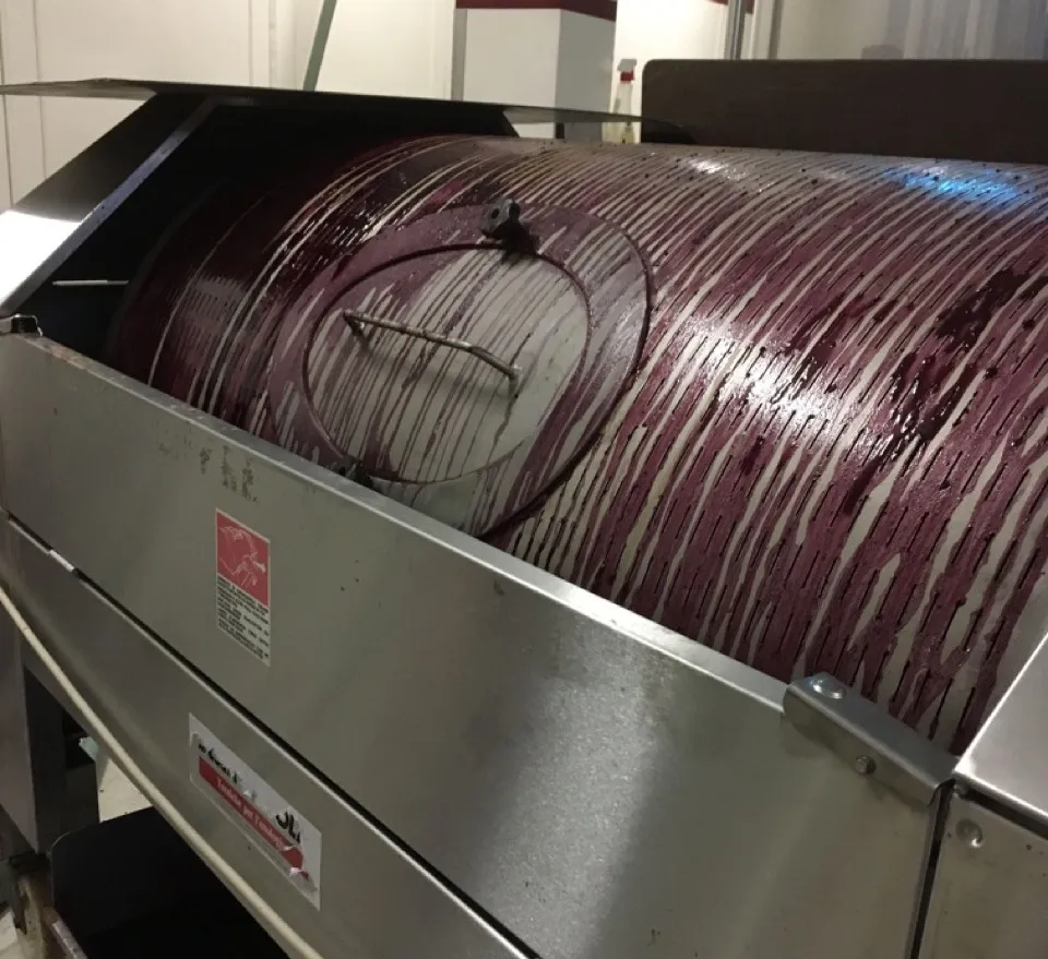 Torchio in azione con acini d'uva rossa all'interno